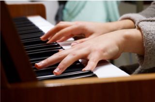 Child playing a piano, focus is on her hands.